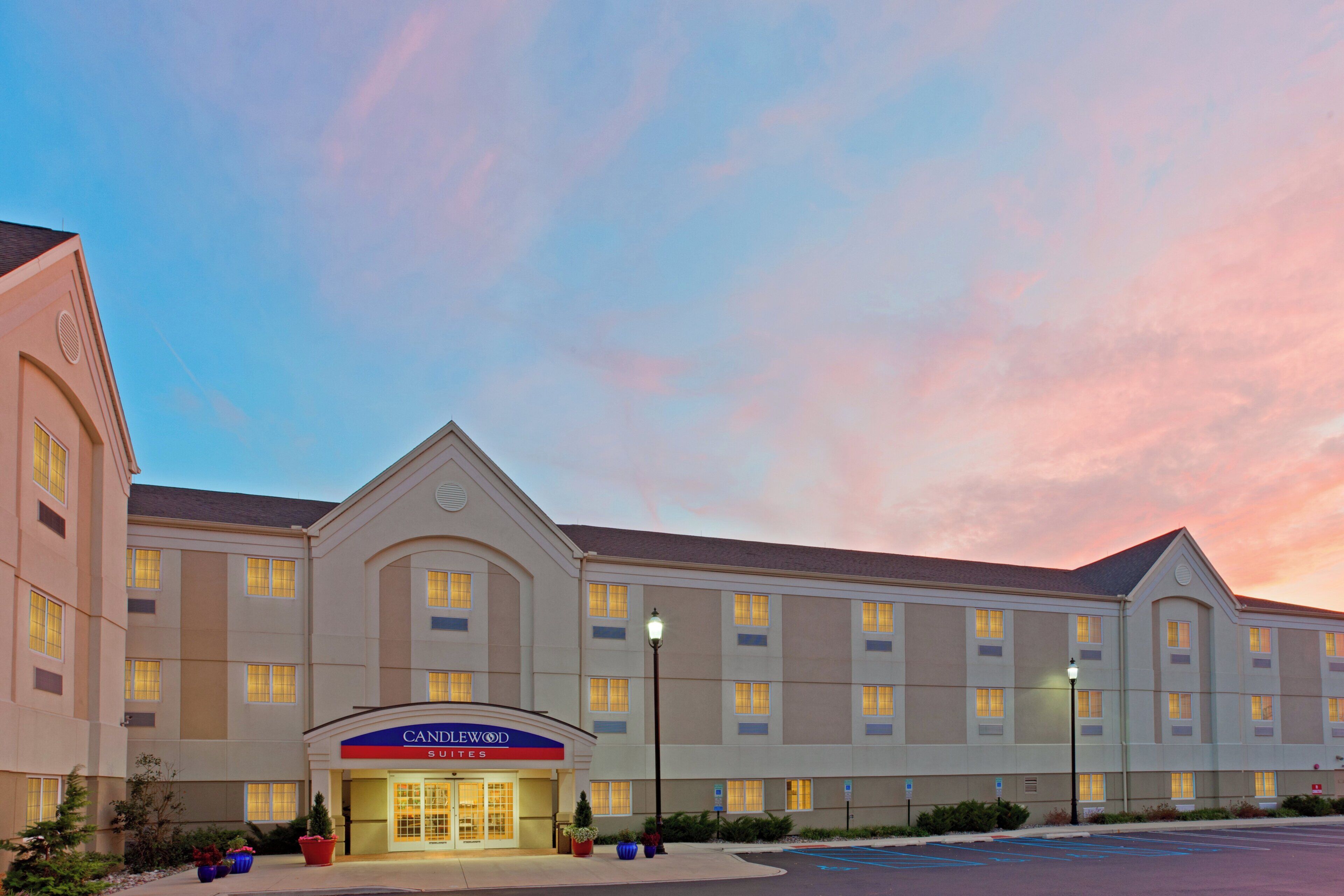 A hotel with a flat facade, multiple windows, and a sign reading 'CANDLEWOOD SUITES.'