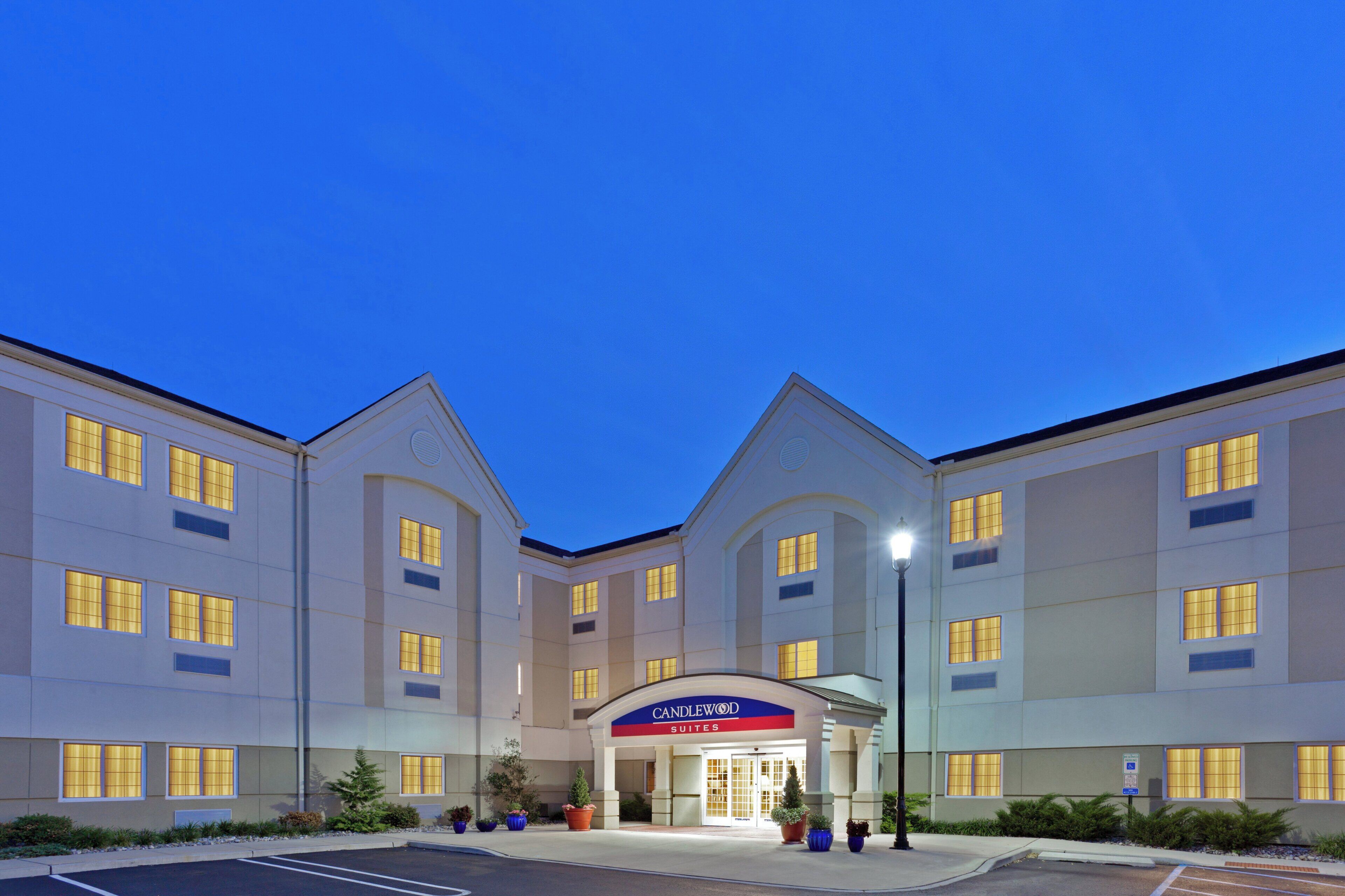 A hotel with a central entrance, multiple windows, and a sign reading 'Candlewood Suites'.