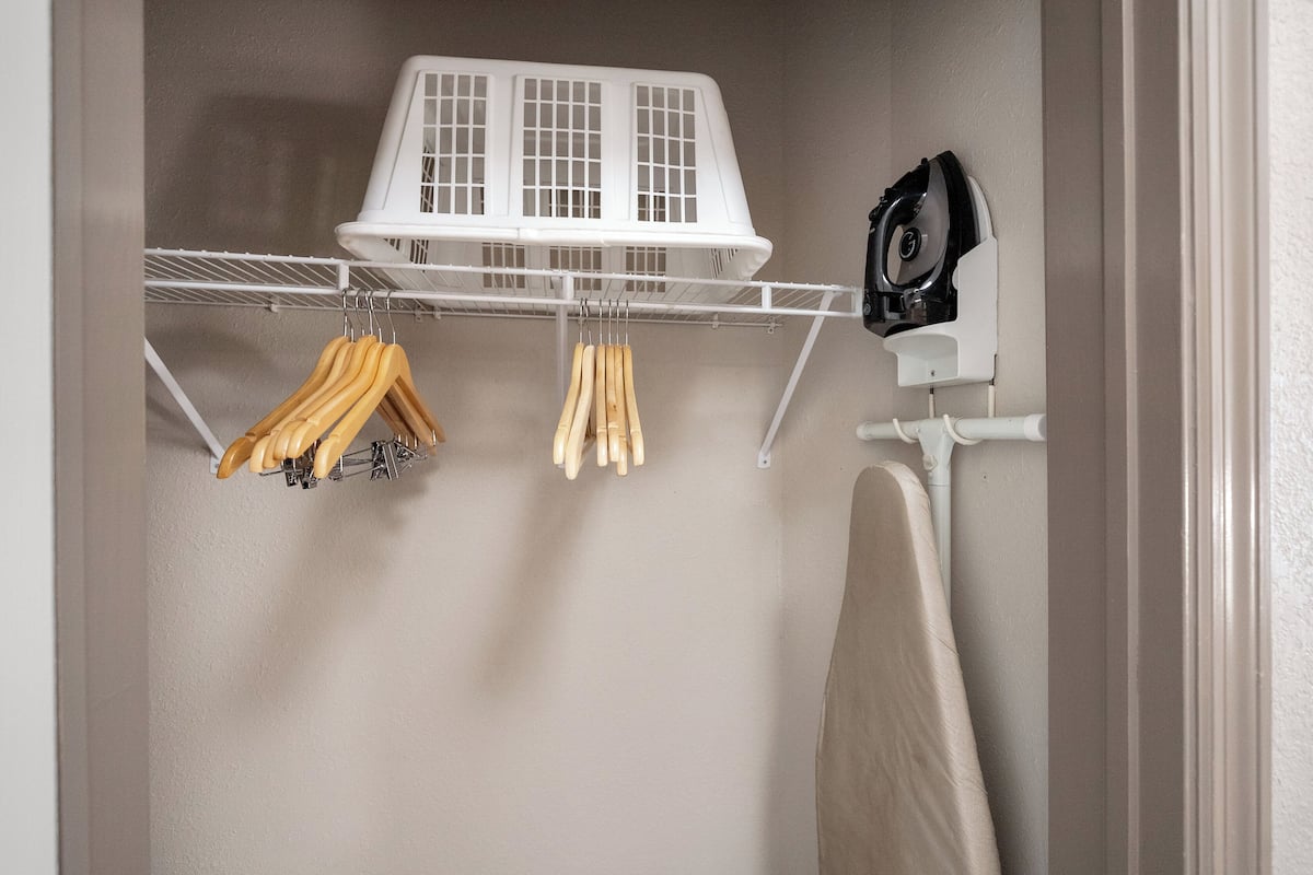 A laundry area with a drying rack, a drying machine, and wooden hangers hanging on a wall-mounted rack.