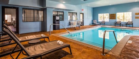 A pool area with lounge chairs, a pool, and a staircase leading to an upper level.