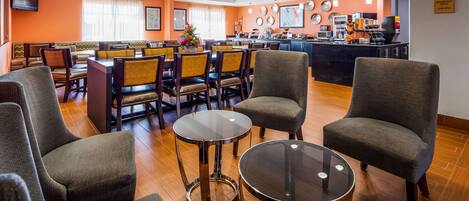 Un vestíbulo de hotel con zonas de estar, un bar y un área para desayunar.