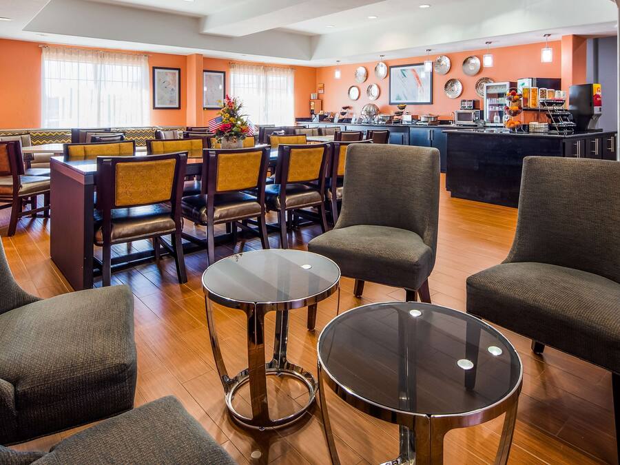 A hotel lobby with seating areas, a bar, and a breakfast area.