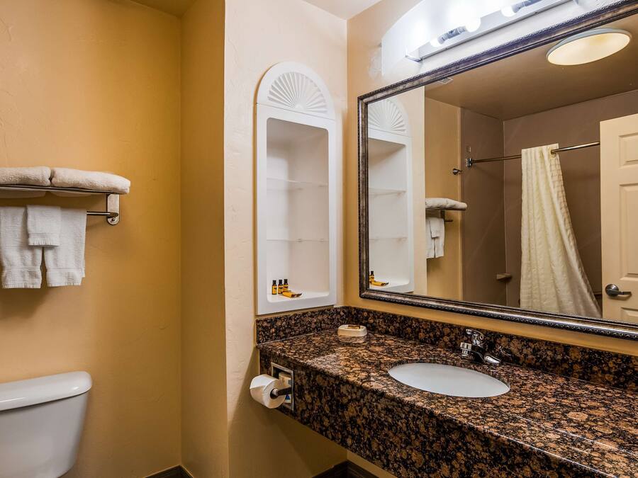 A bathroom with a toilet, sink, and mirror.