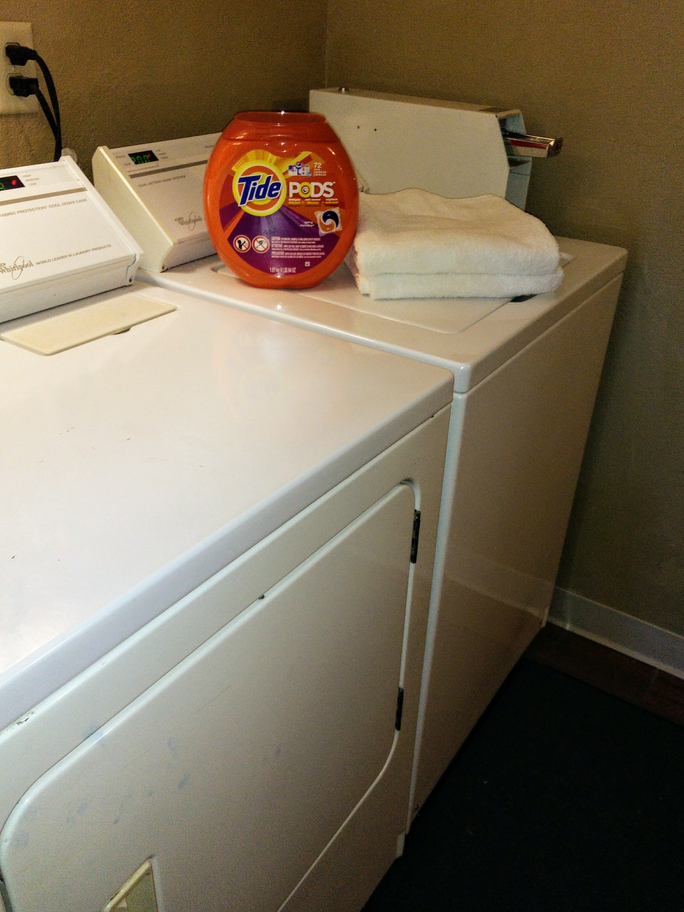 A front-loading washing machine with Tide PODS detergent on top.