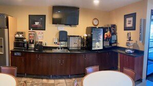 A kitchen with a microwave, toaster, coffee machine, and refrigerator. There is a trash can and a clock on the wall. - Super 8 by Wyndham Chisago City (Chisago City)