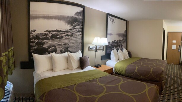A hotel room with two beds, a nightstand, a lamp, and a large framed picture on the wall. - Super 8 by Wyndham Chisago City (Chisago City)