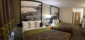 A hotel room with two beds, a nightstand, a lamp, and a large framed picture on the wall. - Super 8 by Wyndham Chisago City (Chisago City)