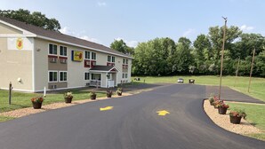 A hotel with a parking lot, marked directional arrows, and potted plants along the curb. - Super 8 by Wyndham Chisago City (Chisago City)