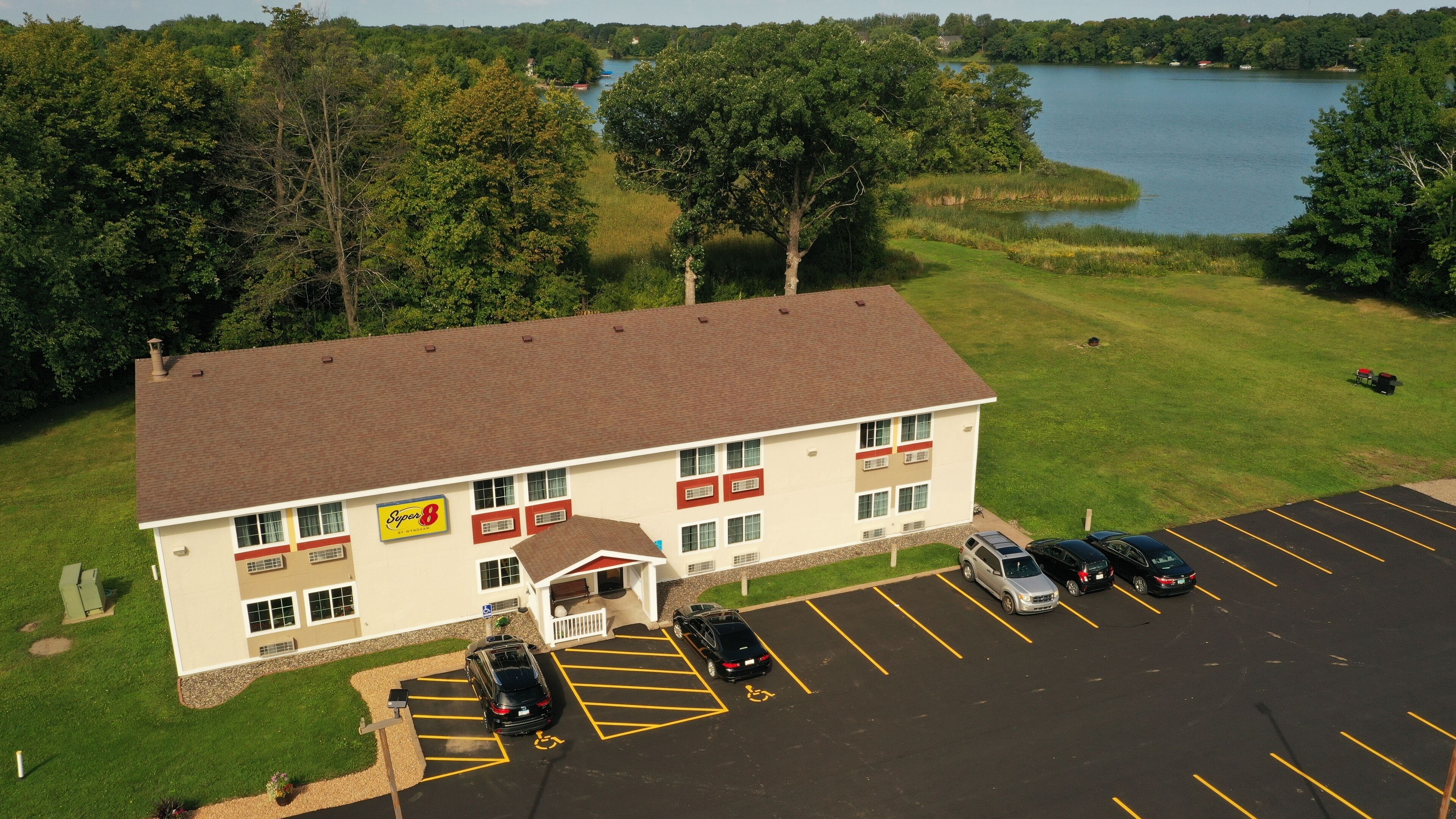 A Super 8 motel with a parking lot, a lake view, and a grassy area.