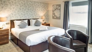 A neatly arranged bedroom with a large bed, two bedside tables, a chair, and a window with curtains. - Lord Haldon Country Hotel, Sure Hotel Collection by Best Western (Exeter)