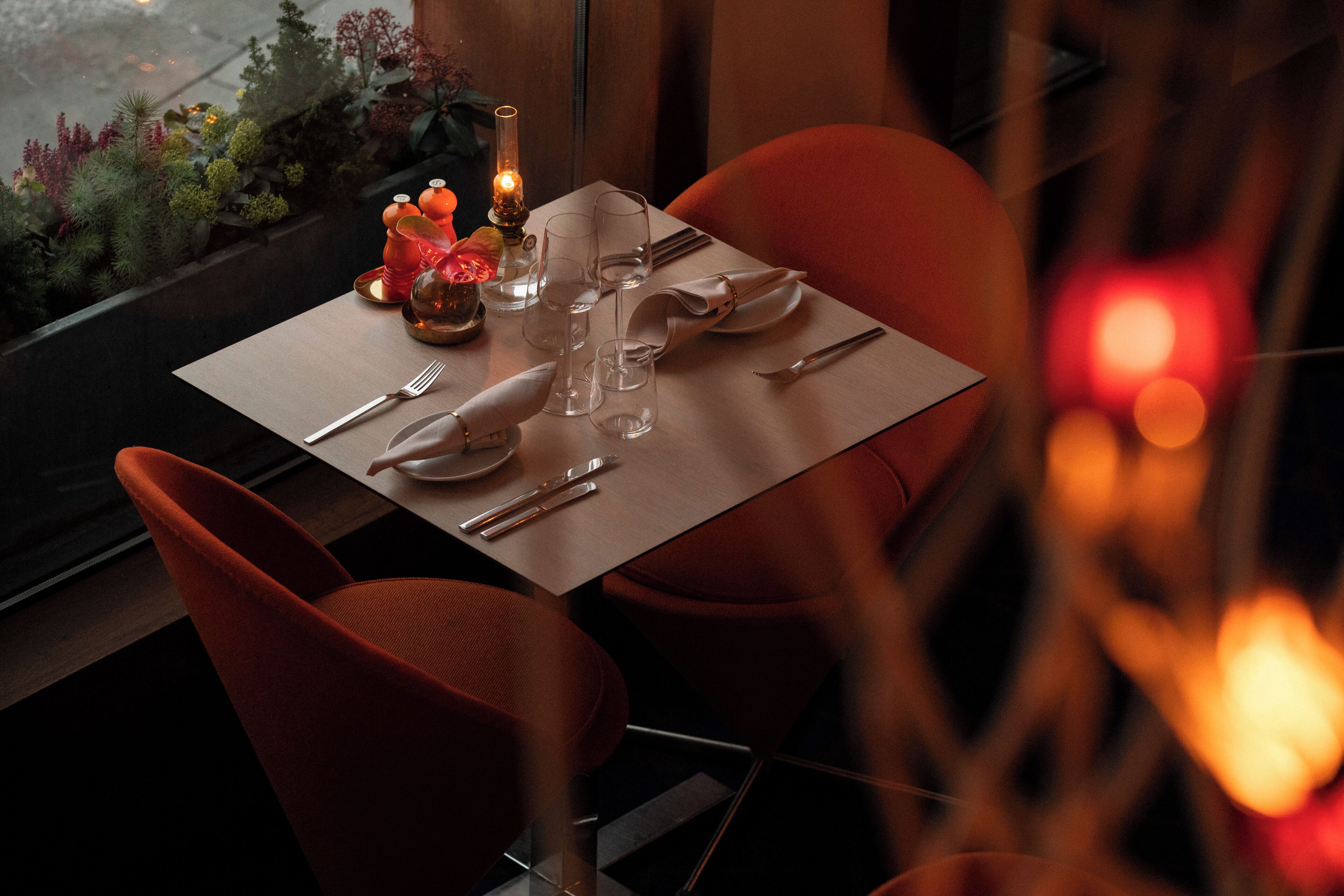 A dining table set with a candle, glasses, and cutlery.