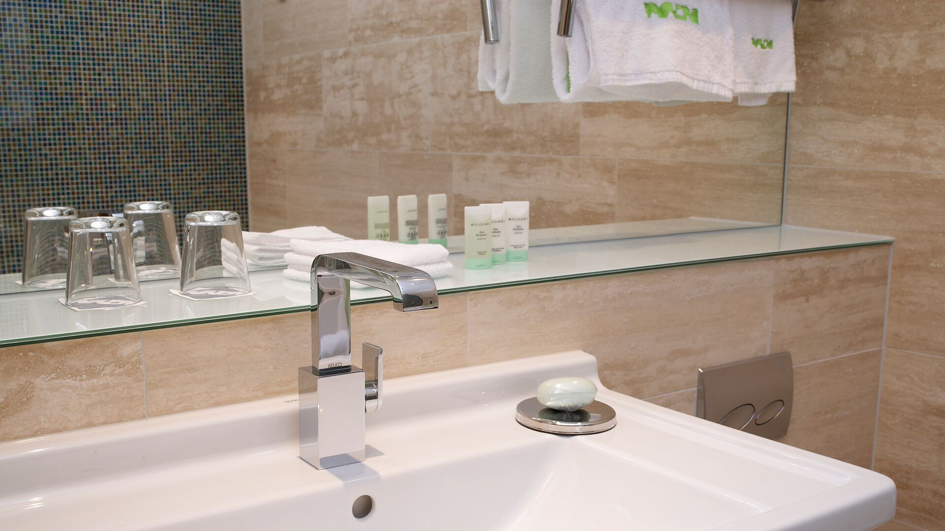 Un baño moderno con repisas de vidrio para artículos de aseo y un espejo sobre el lavabo.