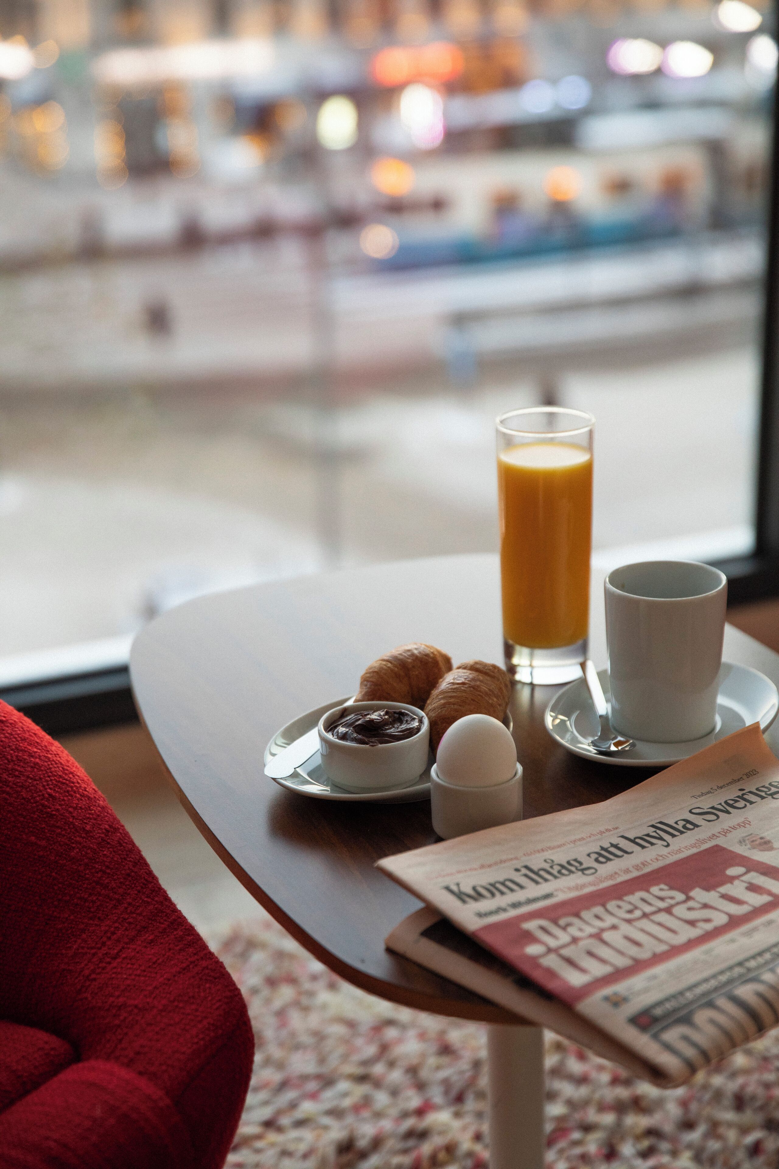 Una mesa de desayuno con cruasanes, un vaso de zumo de naranja y un periódico titulado "Dagens Industri".