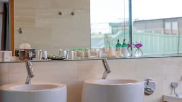 Et badeværelse med to håndvaske, et spejl og toiletartikler på bordet.