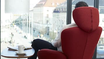 En person sitter i en röd stol vid ett fönster med utsikt över en stadsgata.