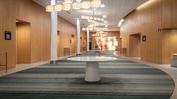 Un hall espacioso con una mesa redonda central, paneles de madera y una alfombra estampada.