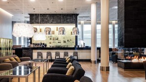A modern lounge area with sofas, tables, a bar, and a fireplace.