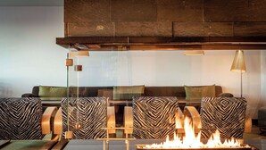 A modern living room with a fireplace, patterned furniture, and a glass partition.
