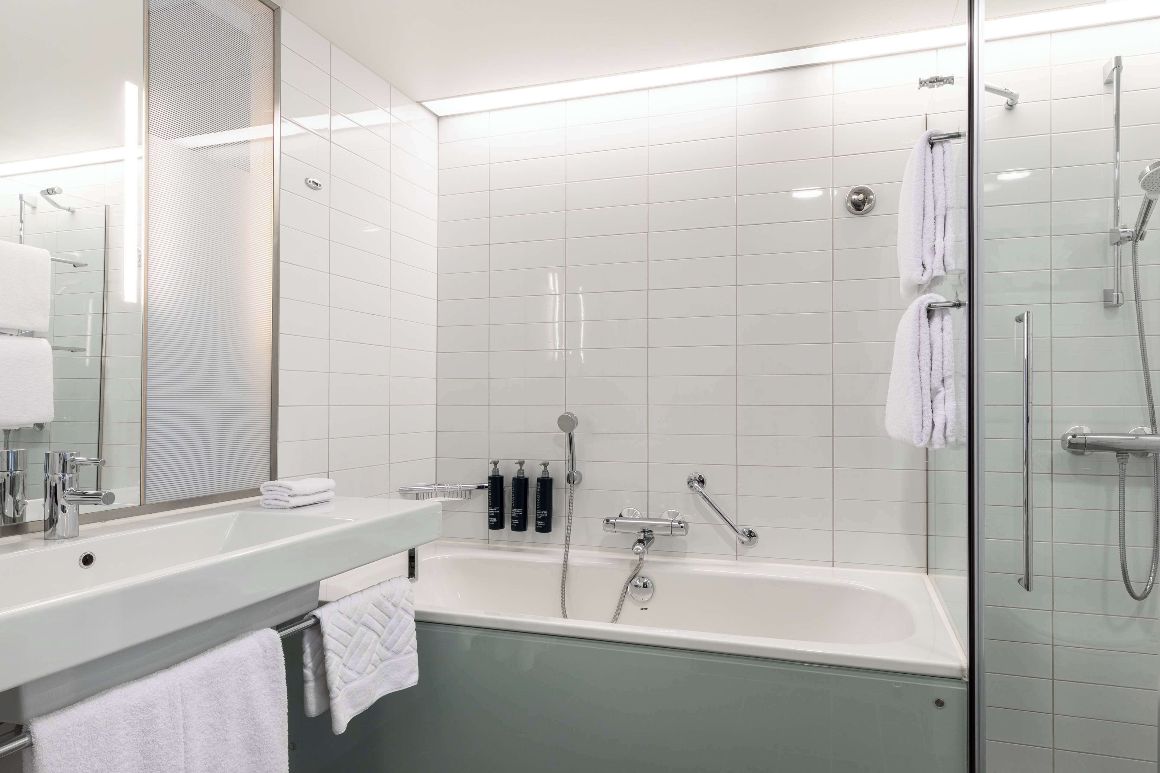 A modern bathroom with a glass-enclosed shower, a freestanding bathtub, and a vanity with a mirror and sink.