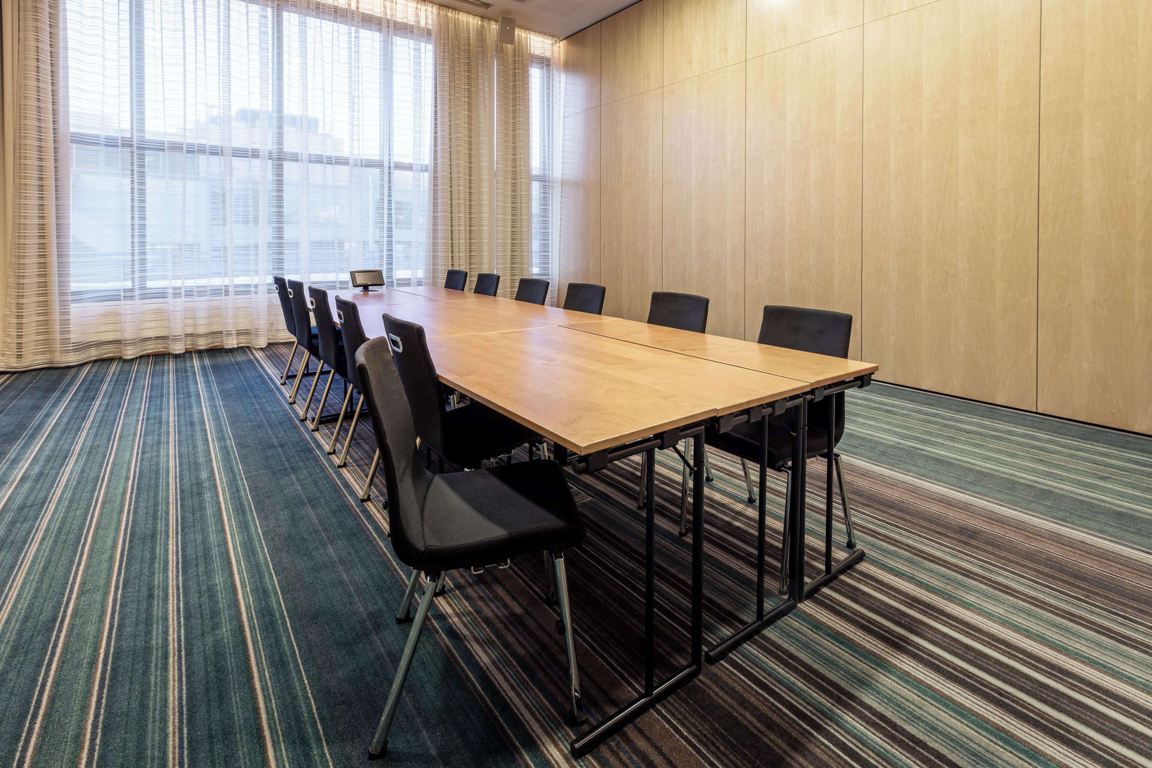 A conference room with a long table, chairs, and a carpeted floor.