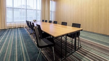 A conference room with a long table, chairs, and a carpeted floor.