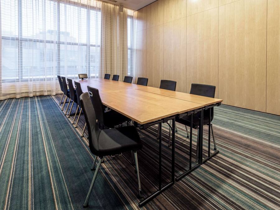 A conference room with a long table, chairs, and a carpeted floor.