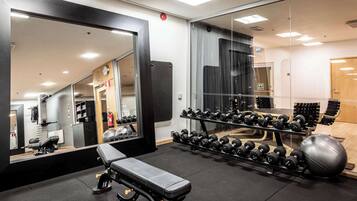 Ein Fitnessraum mit einer Bank, Kurzhanteln und Trainingsbällen.