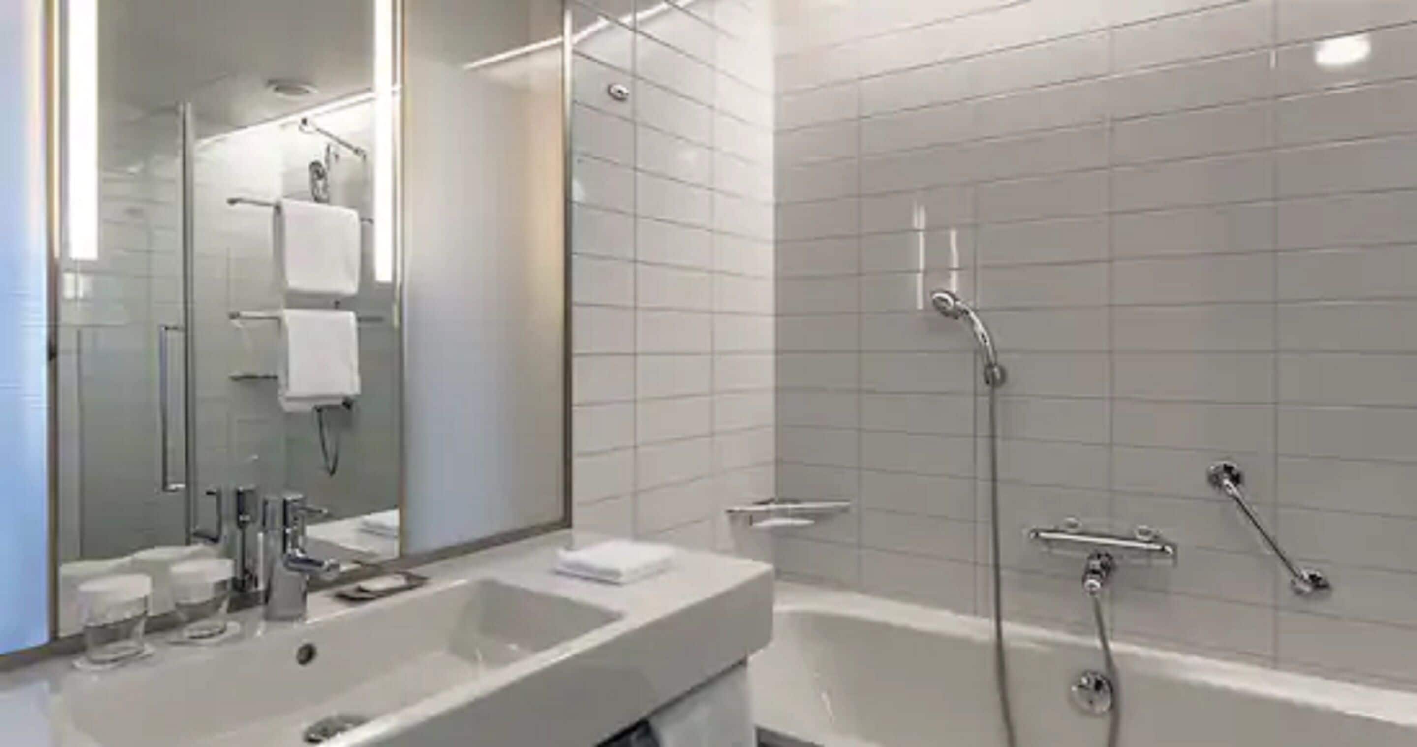 Une salle de bain moderne avec un grand miroir, un lavabo et une baignoire.