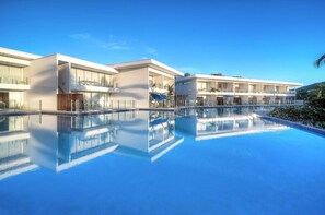 A modern hotel with a large swimming pool, multiple balconies, and a clear blue sky. - Pool Port Douglas (Port Douglas)