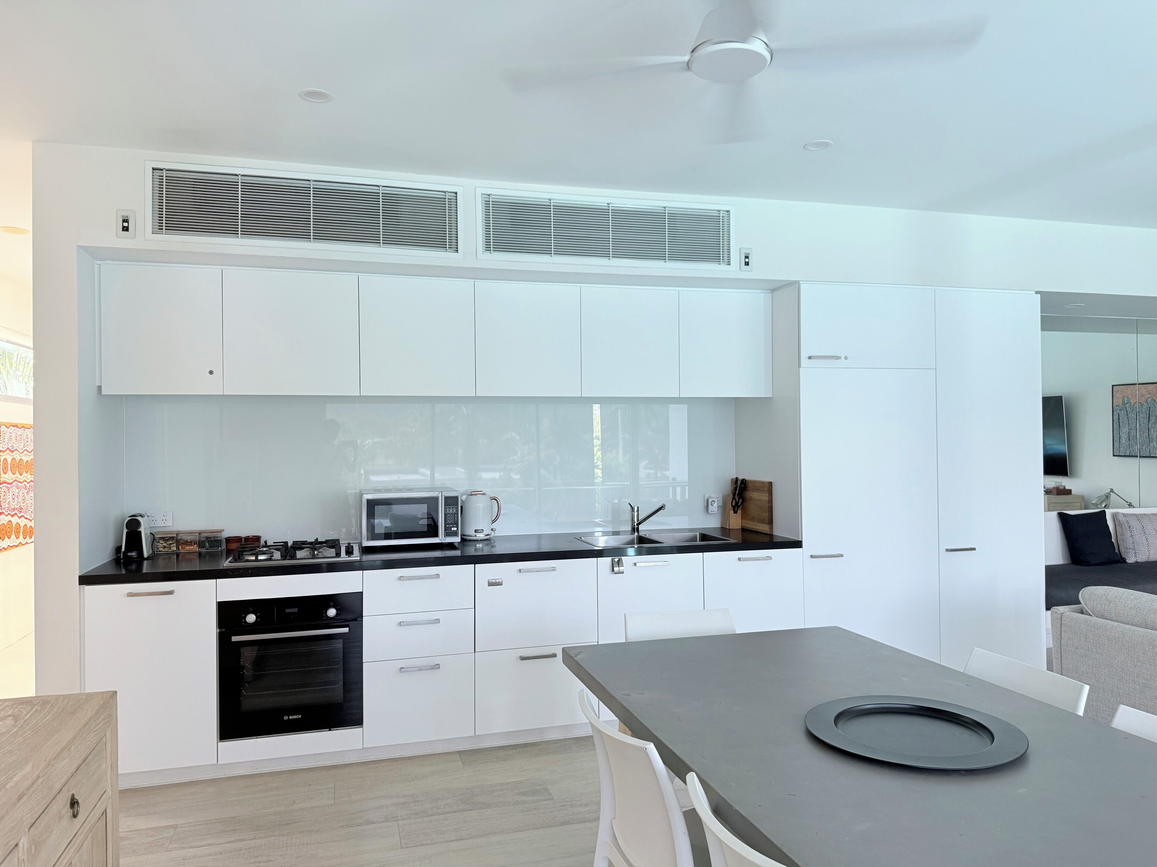 A modern kitchen with white cabinetry, a black countertop, and a Bosch oven.