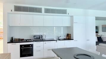 A modern kitchen with white cabinetry, a black countertop, and a Bosch oven.