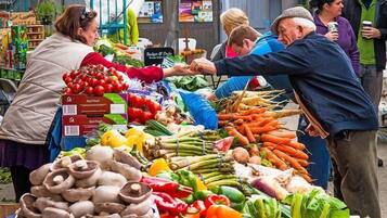 A bustling outdoor market with various fresh vegetables and fruits on display.