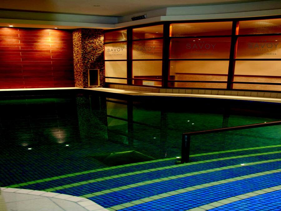 Una piscina interior con escalones revestidos de azulejos que bajan al agua, rodeada de paredes con la señalización 'The Savoy'.