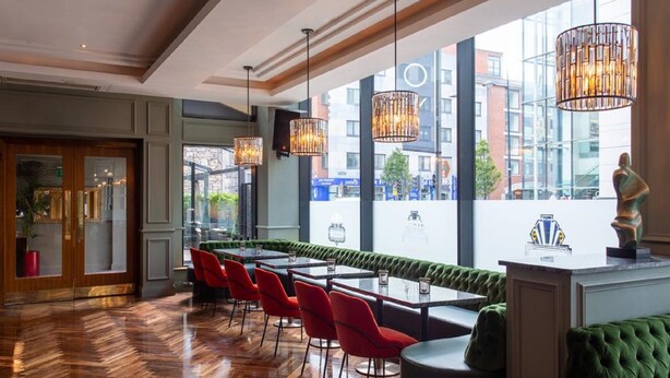 Un restaurant avec un long comptoir, des chaises rouges et des sièges recouverts d’un tissu vert.