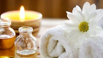 A candle, two glass bottles, and a white towel with a daisy.