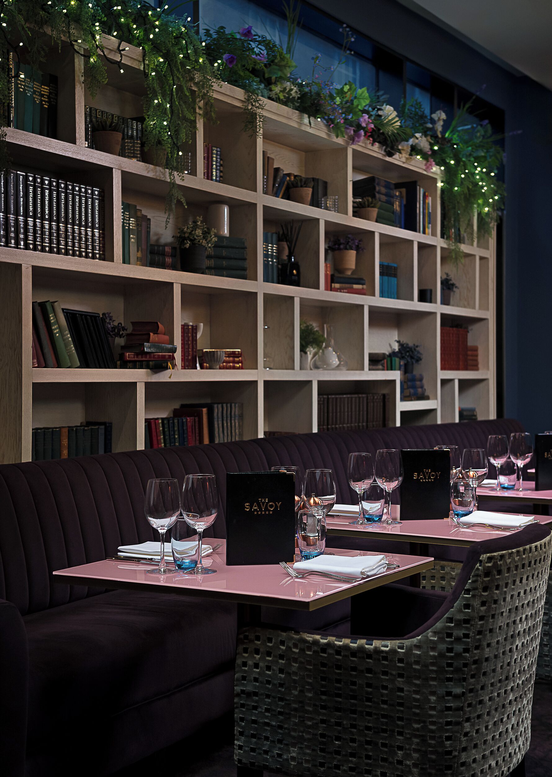 A restaurant with a dark-colored sofa and dining tables set for a meal.