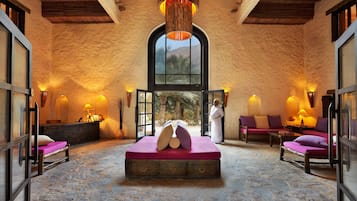 Relax in this spacious room with a large bed, two seating areas, and a high ceiling with wooden beams.