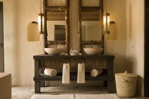 A rustic bathroom with a wooden vanity, two mirrors, and a woven basket.