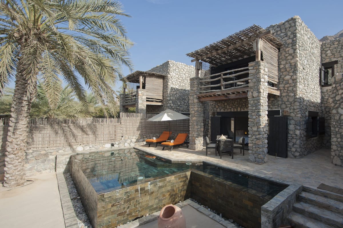 Eine Steinvilla mit Swimmingpool, Außenbereich zum Sitzen und einer Pergola.