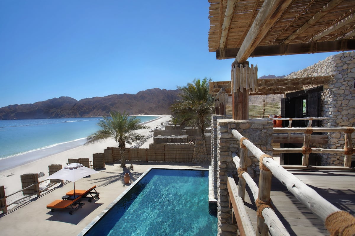 Ein Poolbereich mit Blick auf Strand und Berge.
