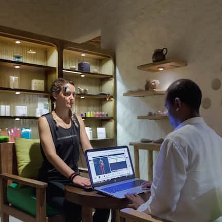 A room with wooden furniture, shelves with items, and a laptop on a table.