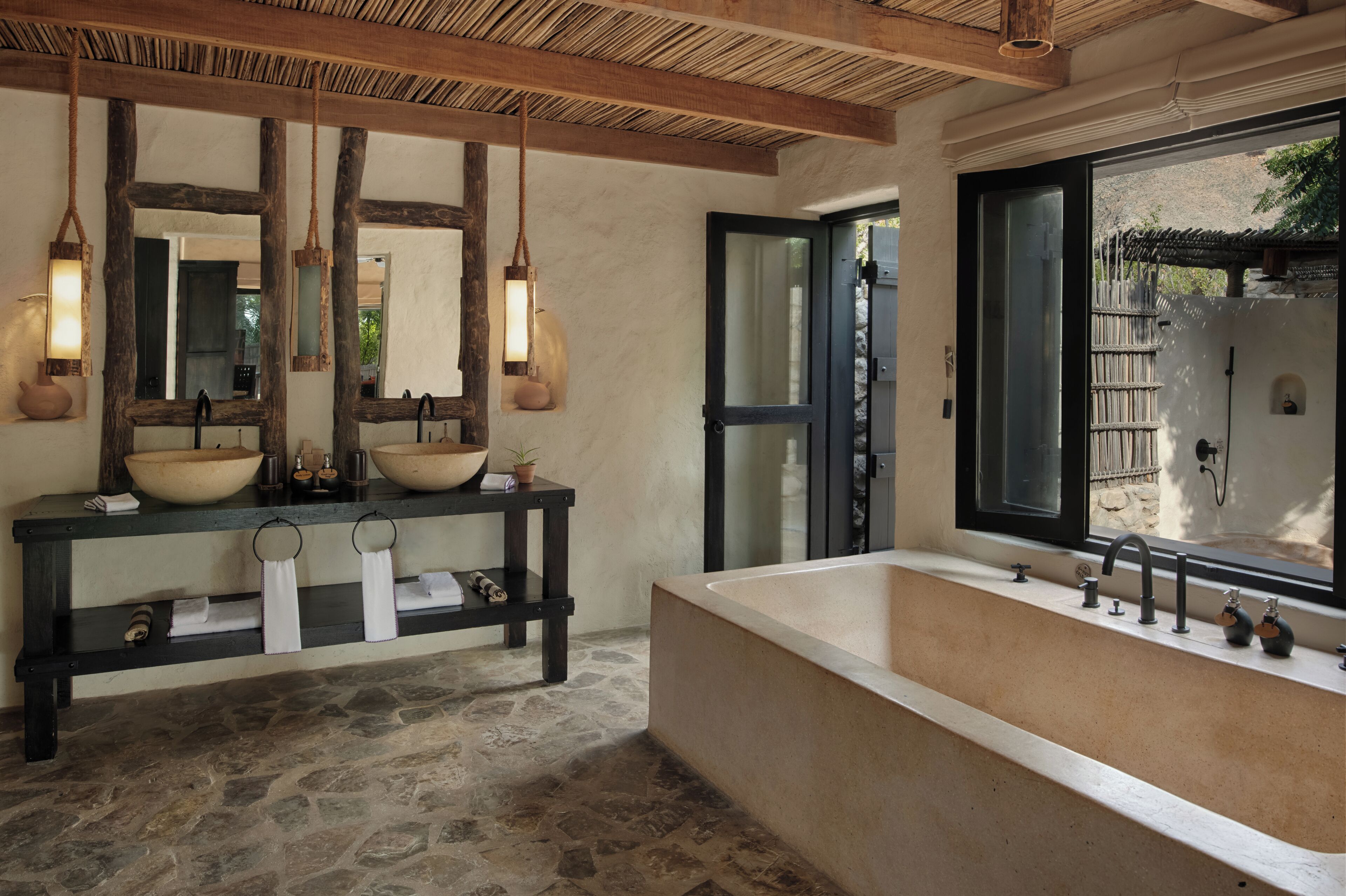 A bathroom with a large bathtub, a wooden vanity with two large bowls, and a mirror.