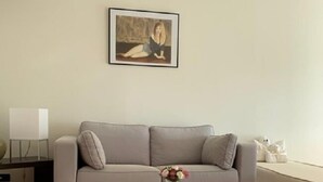 A modern living room with a grey sofa, a coffee table with a vase of flowers, and a framed picture on the wall. - PAVILLON BEL AIR (Cannes)
