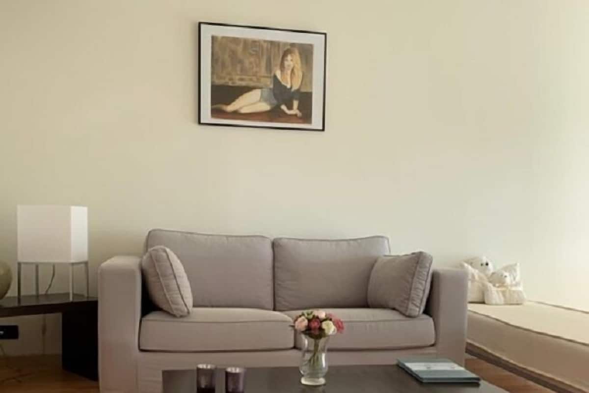 A modern living room with a grey sofa, a coffee table with a vase of flowers, and a framed picture on the wall.