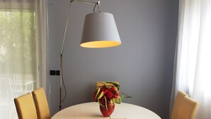 A dining area with a round table, four chairs, a vase with flowers, and a pendant light. - PAVILLON BEL AIR (Cannes)