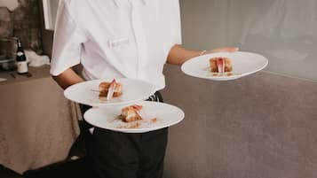 A person in a white shirt holding two white plates with cake slices.