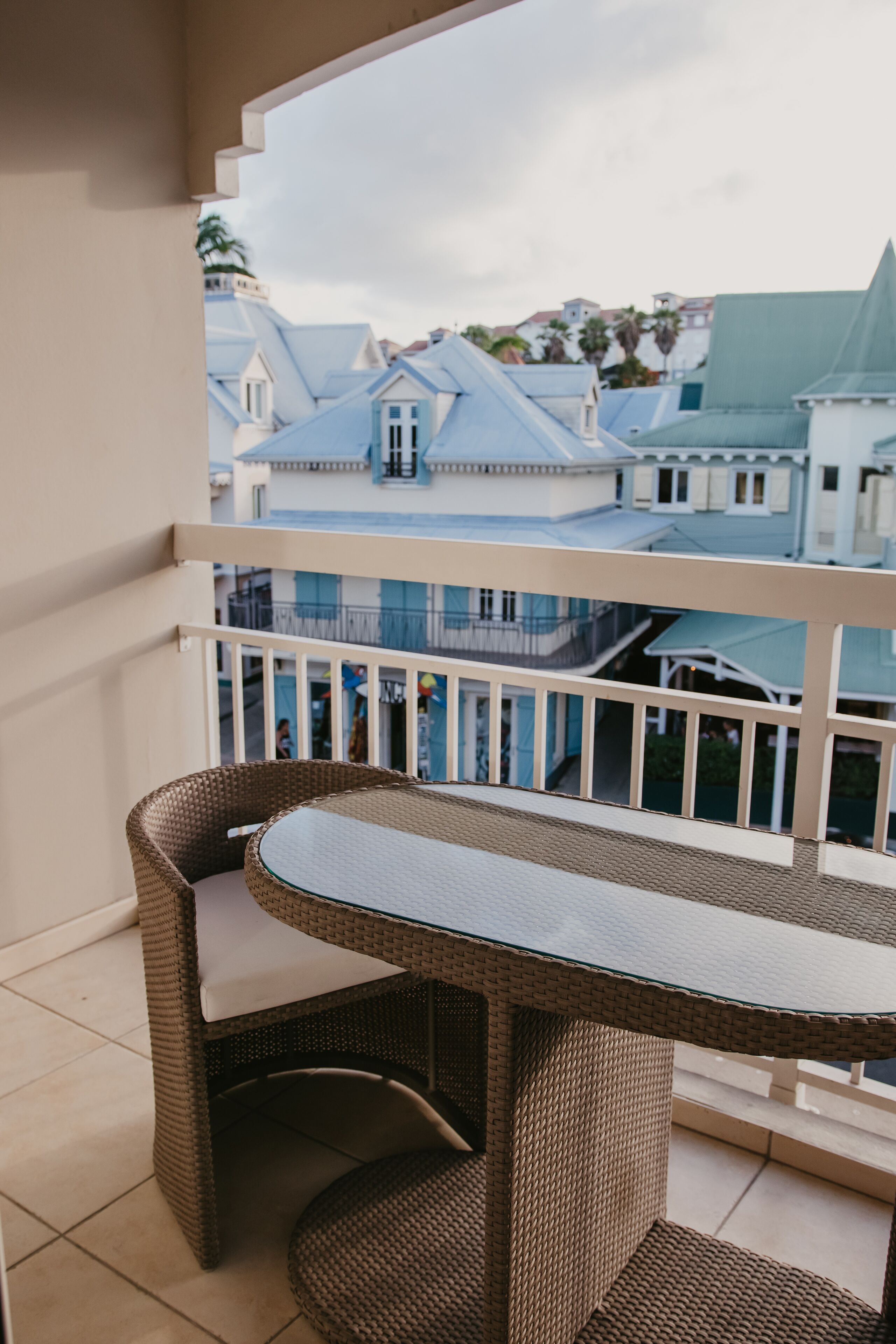 A balcony with wicker furniture and a view of buildings.