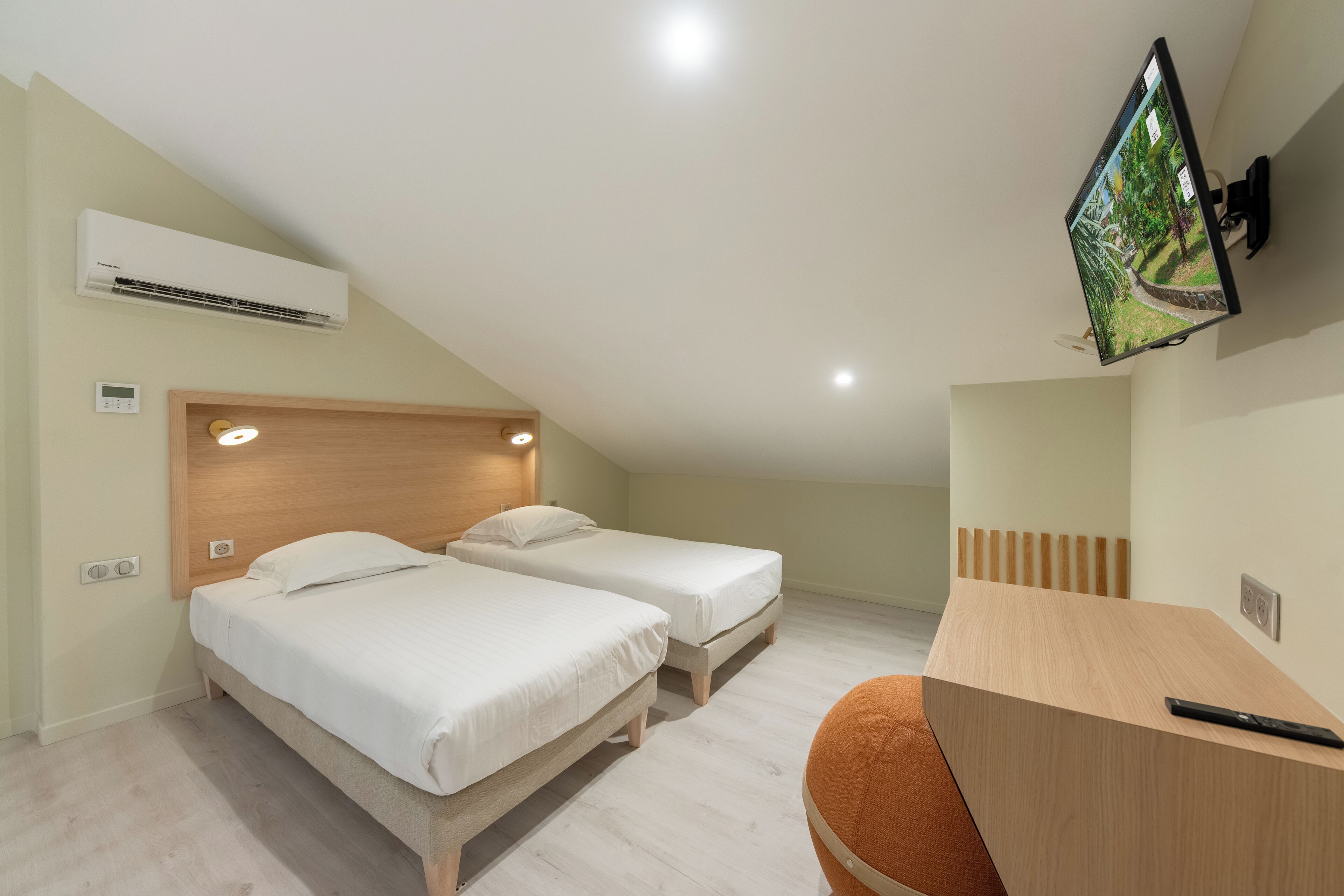 Une chambre avec deux lits, un bureau, une télévision et un climatiseur.