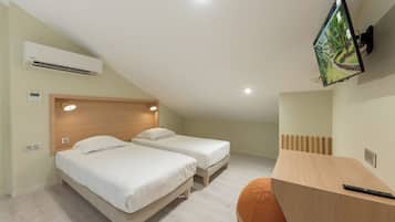 Een slaapkamer met twee bedden, een bureau, een televisie en een airconditioner.