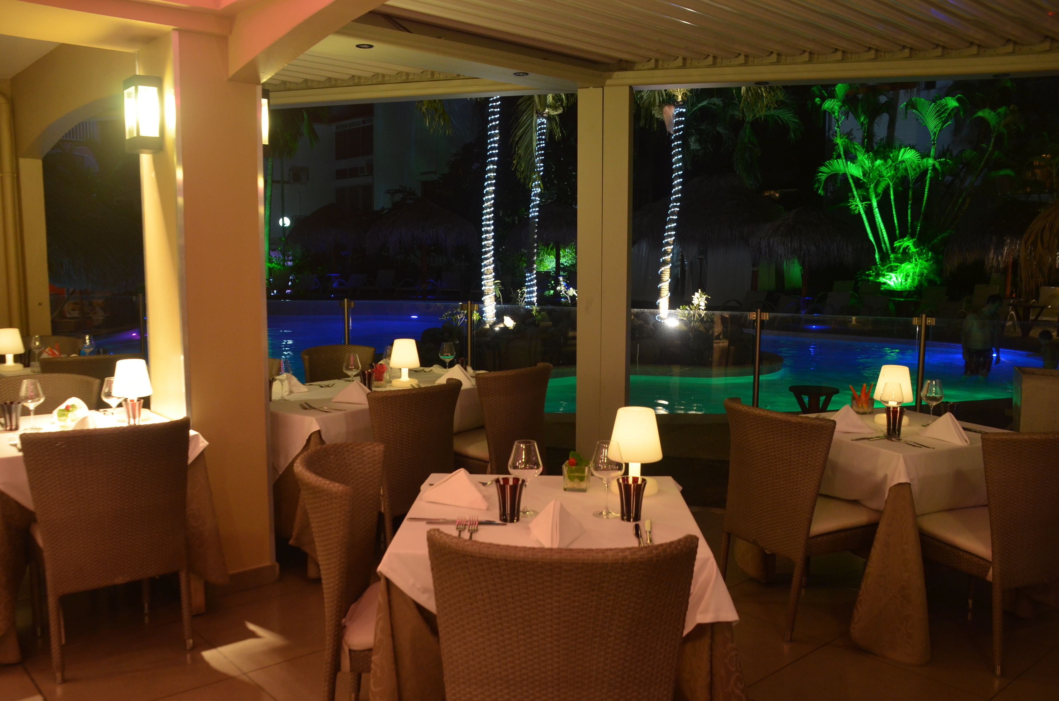 Un restaurante con mesas dispuestas para comer, una piscina con fuente de agua y vistas al área de la piscina.